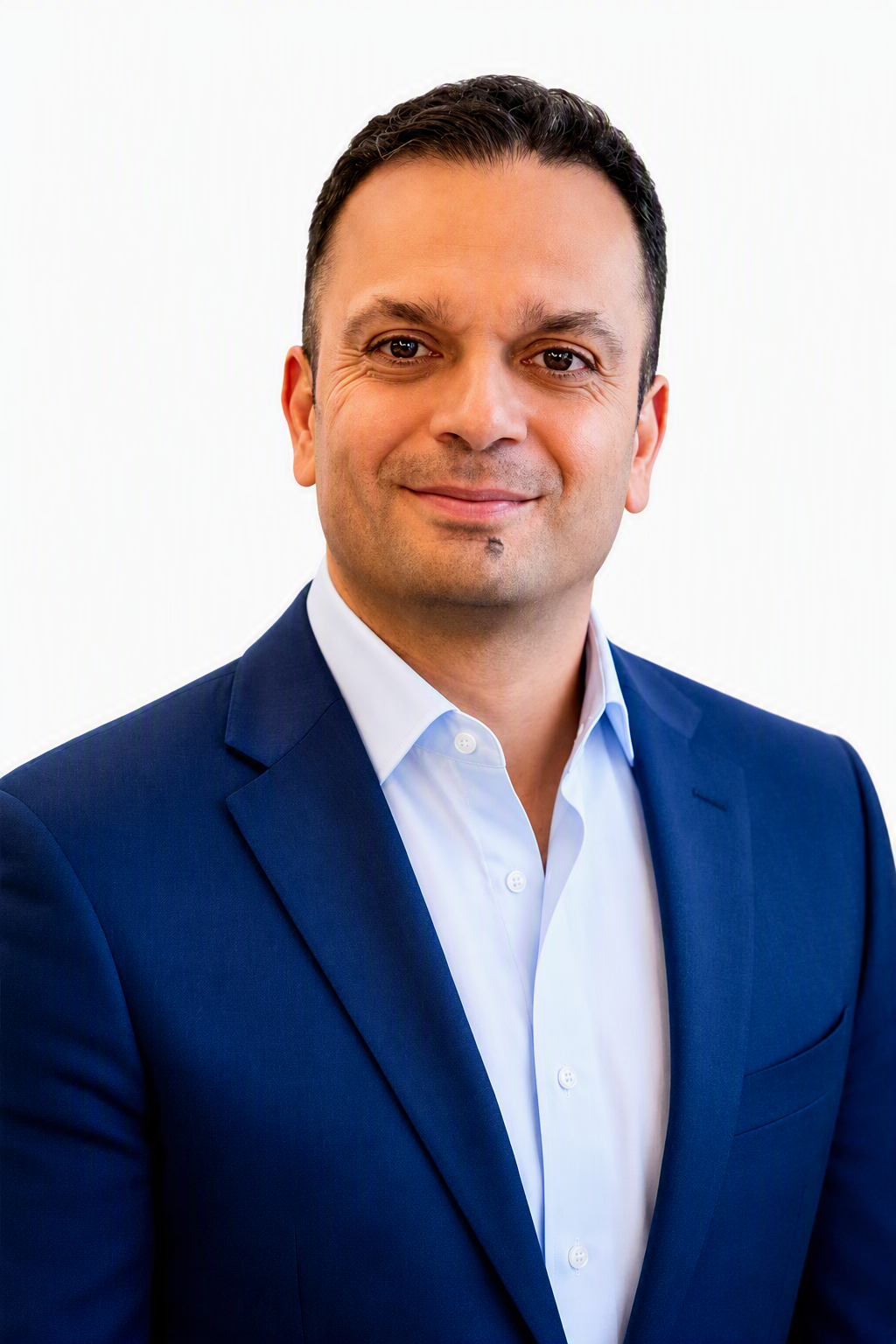 Man in a blue suit and white shirt smiles at the camera against a plain white background.